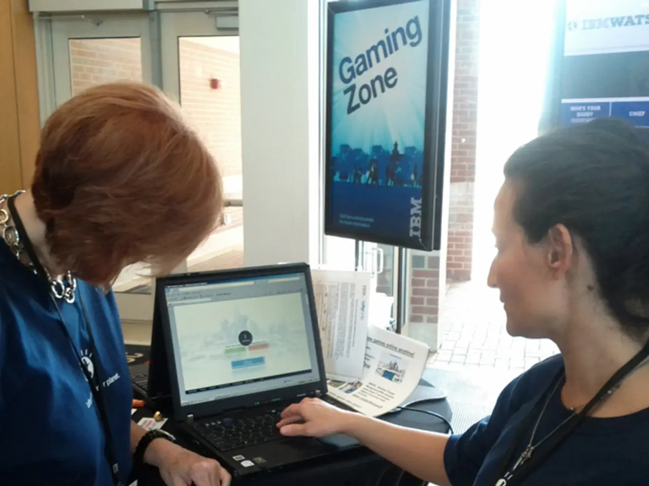 In the image there are two people in the foreground, on the right side there is a woman, she is...