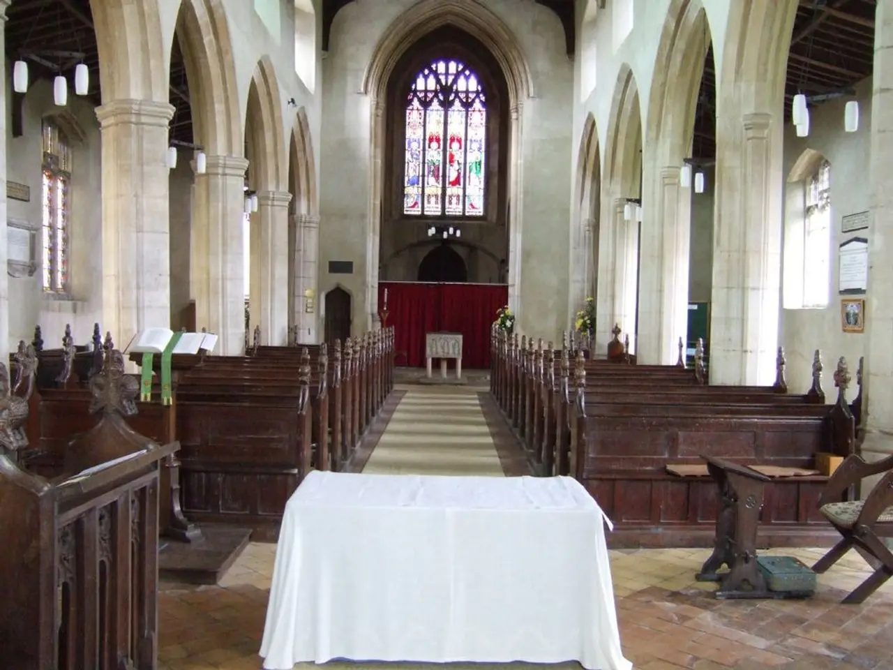 In this image there are tables, podium, book stand, chair, benches, pillars, boards, curtain,...