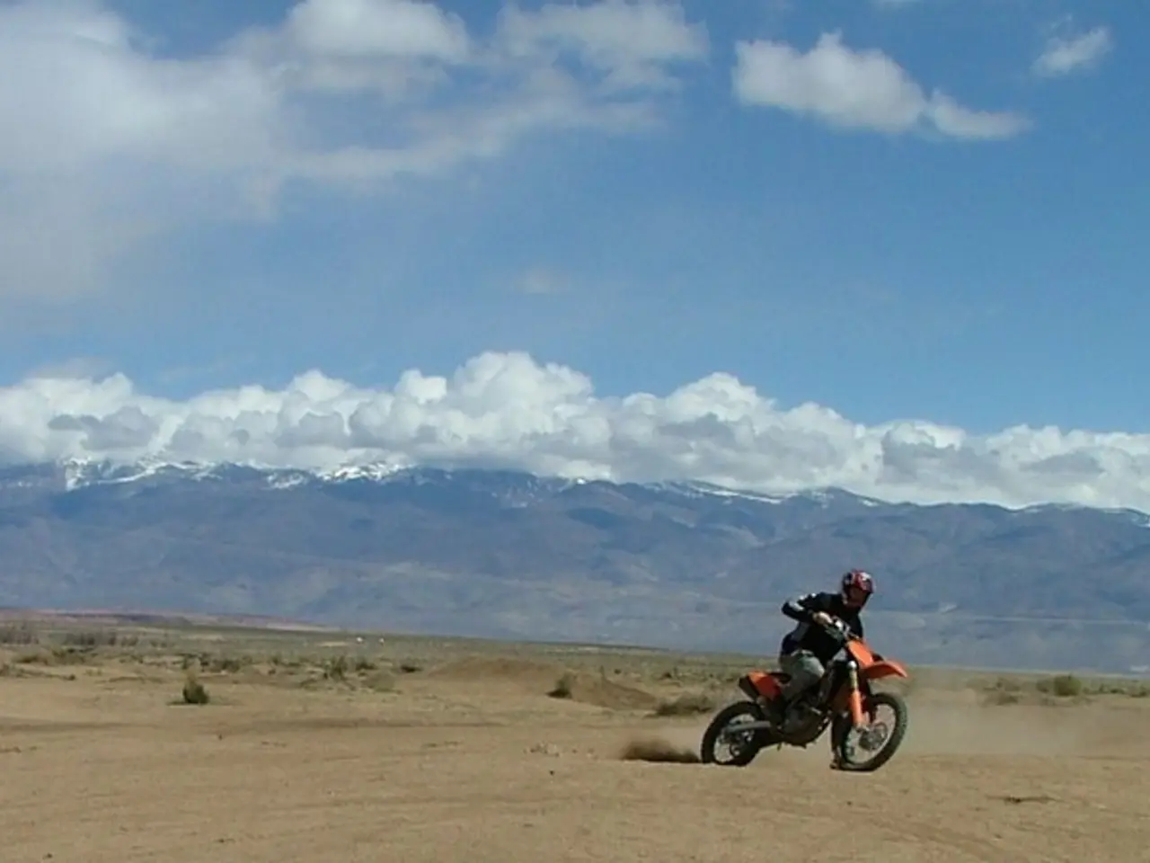 As we can see in the image there is grass, current polls, a man riding motor cycle,s hills, sky and...