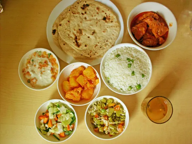 In the foreground I can see a plate in which chapatis are there and bowls in which curries, salad,...