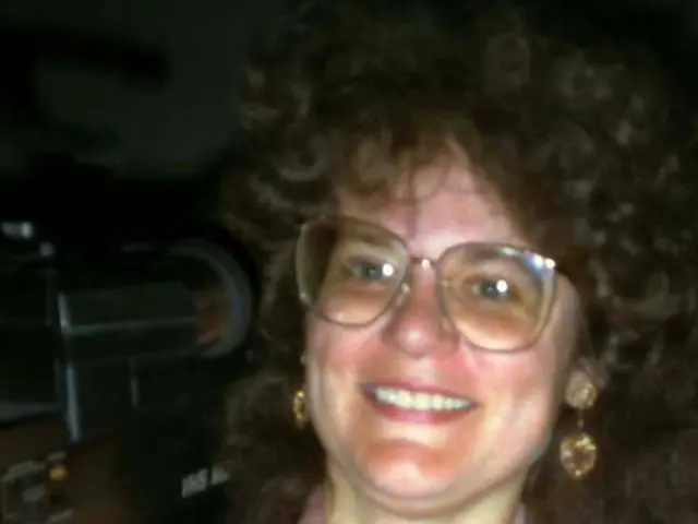 In this image we can see woman holding video camera.