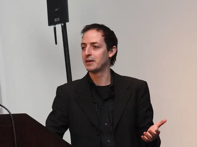 A man is standing wearing suit, these are bottles and cables, this is wall.