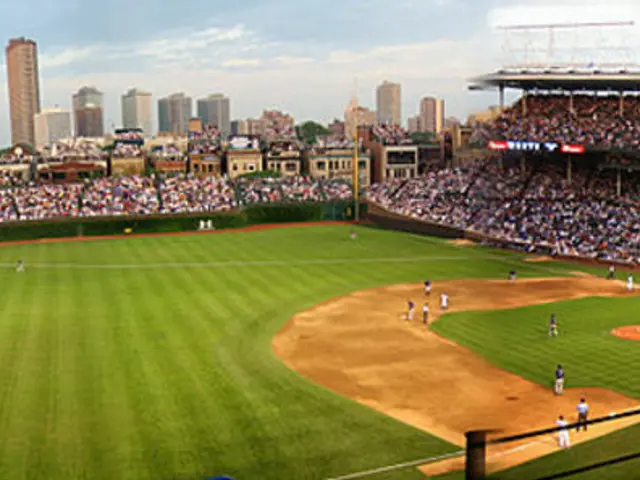 This is an aerial view image of a baseball stadium, there are many people sitting all around the...