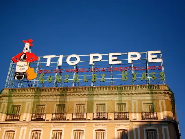 In this image there is a building with net and name boards , and in the background there is sky.