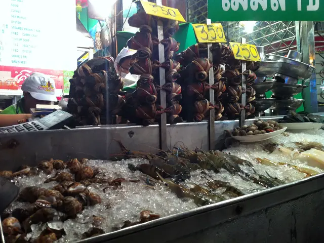 In this picture there is a shop with many hanging crabs. In the front there is big steel vessel...