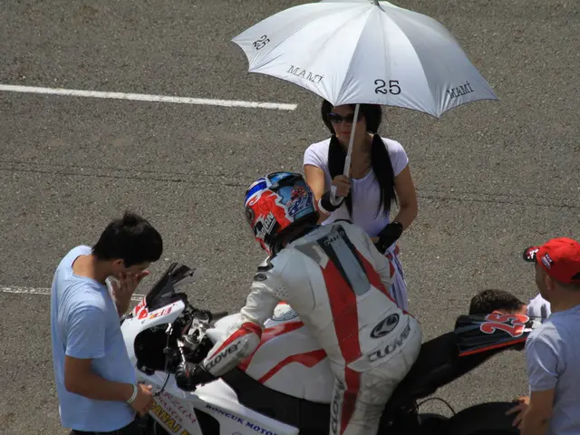 This is a picture taken in the outdoor. The man in white suit riding a bike on the right side of...