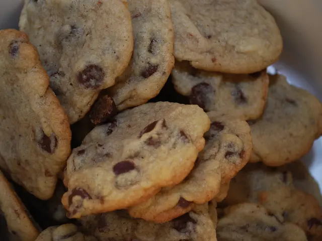 In this image there are so many cookies in the box. On the cookies there are choc chips.