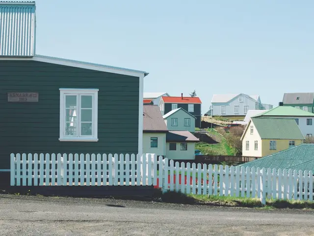 There are many houses in the image. There is a clear sky at the top of the image. There is a grassy...